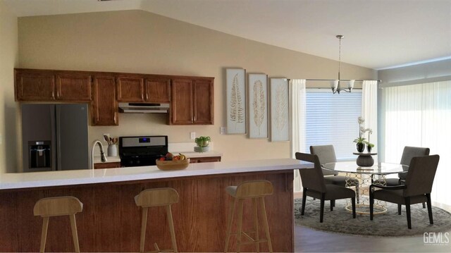 9057 Mackenzie Ct, Bakersfield, CA 93306 - kitchen with black refrigerator with ice dispenser, stainless steel range with gas cooktop, vaulted ceiling, under cabinet range hood, and a breakfast bar area