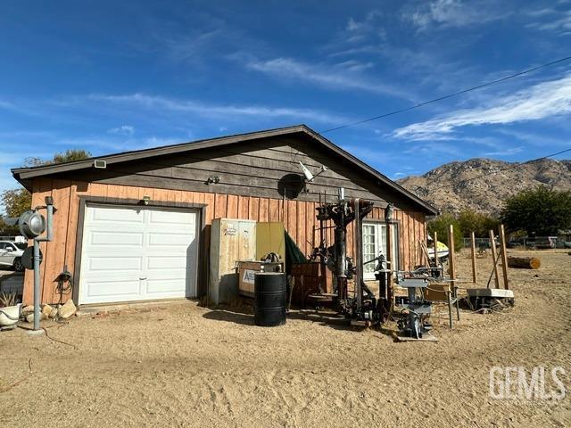 view of side of home featuring a mountain view, a garage, and an outbuilding