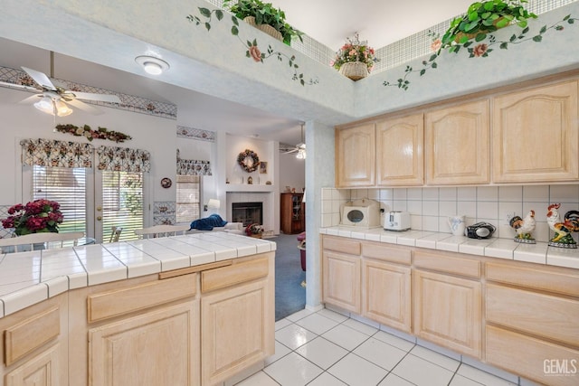 kitchen with tile counters, tasteful backsplash, a ceiling fan, open floor plan, and light brown cabinets