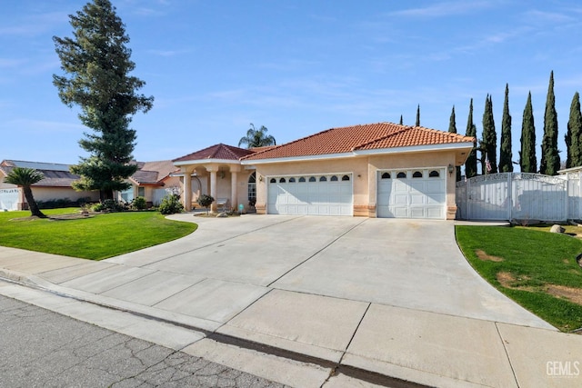 mediterranean / spanish house featuring a tile roof, stucco siding, a gate, a garage, and a front lawn