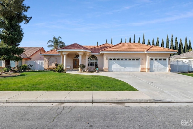 mediterranean / spanish house featuring a garage, concrete driveway, a tiled roof, stucco siding, and a front lawn