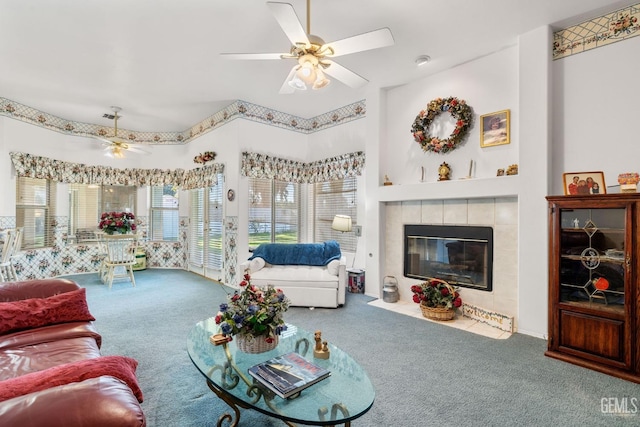 living area with ceiling fan, a tiled fireplace, and carpet