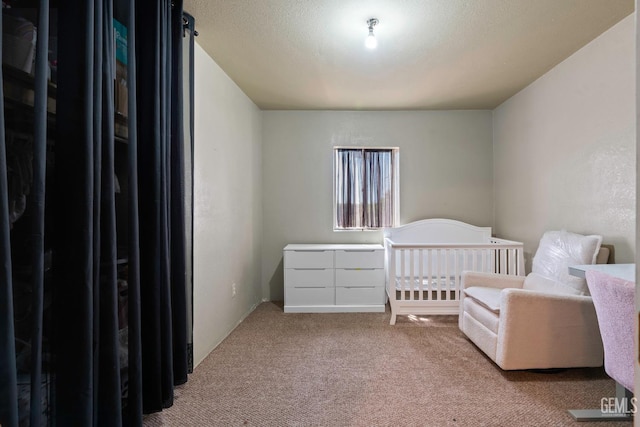 bedroom featuring freestanding refrigerator, light colored carpet, and a textured ceiling