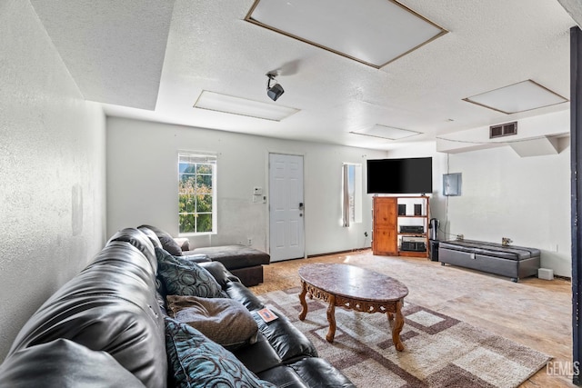 living room featuring a textured wall, visible vents, a textured ceiling, and attic access