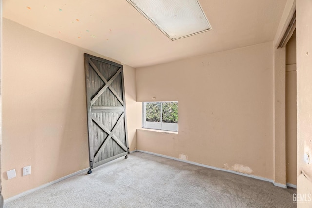 unfurnished room featuring attic access, carpet flooring, and baseboards