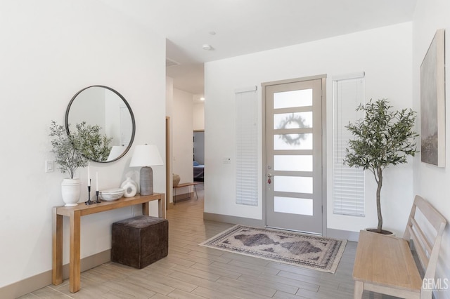 foyer entrance with light wood-style flooring and baseboards