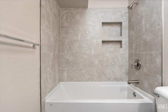 bathroom featuring tiled shower / bath combo and toilet