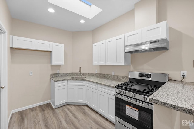 kitchen featuring sink, white cabinets, light stone countertops, stainless steel gas range, and light hardwood / wood-style flooring