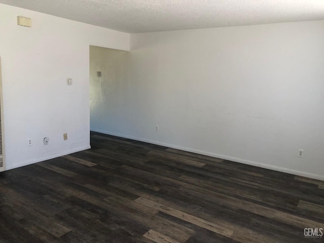spare room featuring baseboards, a textured ceiling, and dark wood-style floors