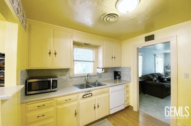 kitchen with dishwasher, light hardwood / wood-style floors, tasteful backsplash, and sink