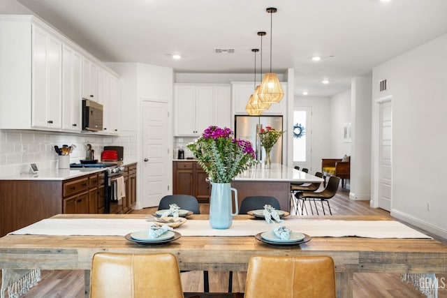 6713 Diamond Springs Dr, Bakersfield, CA 93313 - kitchen featuring stainless steel appliances, a kitchen island, tasteful backsplash, white cabinets, and light wood-type flooring