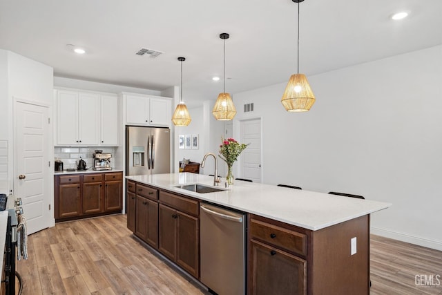 6713 Diamond Springs Dr, Bakersfield, CA 93313 - kitchen with a sink, appliances with stainless steel finishes, white cabinetry, light wood-style flooring, and decorative light fixtures