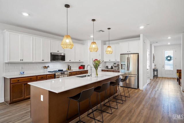 6713 Diamond Springs Dr, Bakersfield, CA 93313 - kitchen with appliances with stainless steel finishes, a sink, tasteful backsplash, light wood-style floors, and a kitchen bar