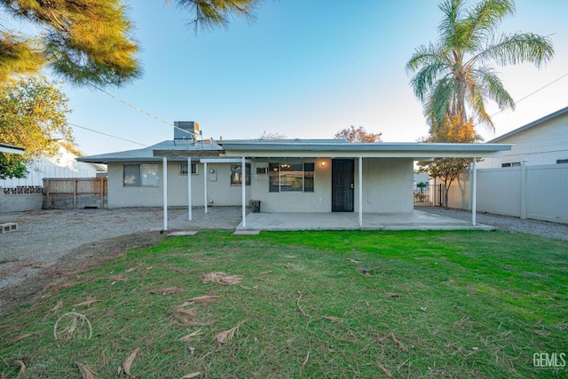 rear view of property featuring a patio area and a lawn