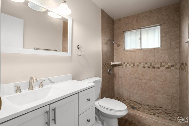 bathroom featuring vanity, toilet, and a tile shower