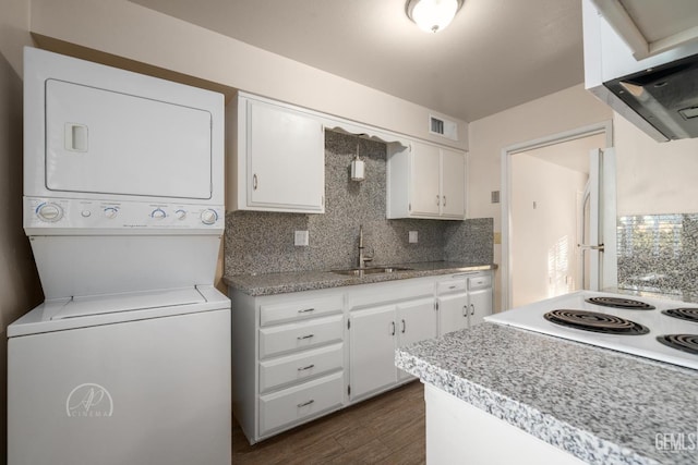 kitchen with sink, white cabinetry, stacked washer / dryer, range hood, and decorative backsplash