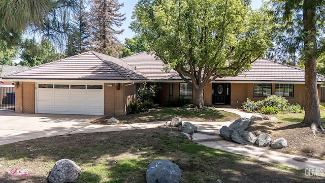 ranch-style home with a tile roof, a garage, driveway, brick siding, and fence