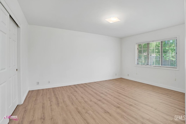 unfurnished bedroom featuring light wood-style floors, a closet, and baseboards