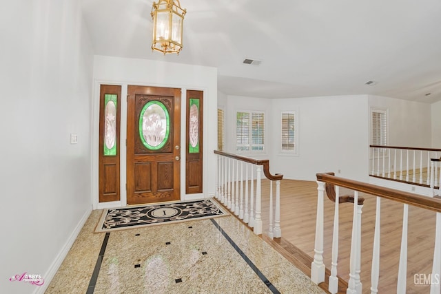 foyer entrance featuring a chandelier, visible vents, and baseboards
