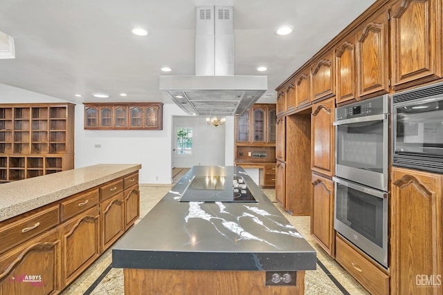 kitchen with double oven, island range hood, black electric stovetop, and brown cabinetry