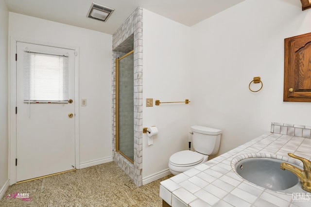 bathroom with tiled shower, toilet, a sink, baseboards, and visible vents