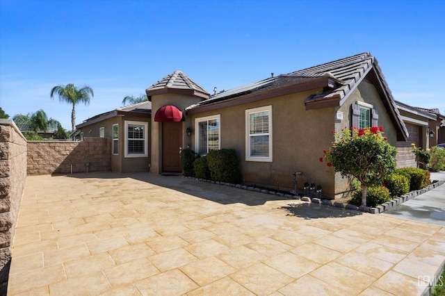10002 Riata Ln, Bakersfield, CA 93306 - view of front of house featuring stucco siding, roof mounted solar panels, a patio, and a tile roof