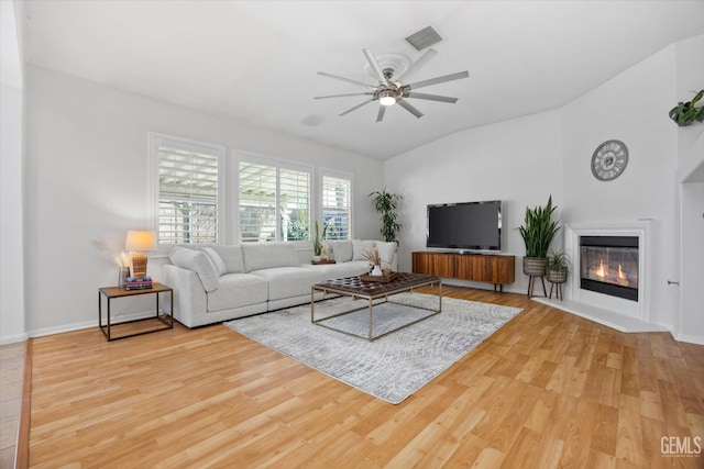 10002 Riata Ln, Bakersfield, CA 93306 - living area featuring wood finished floors, a ceiling fan, lofted ceiling, a glass covered fireplace, and baseboards