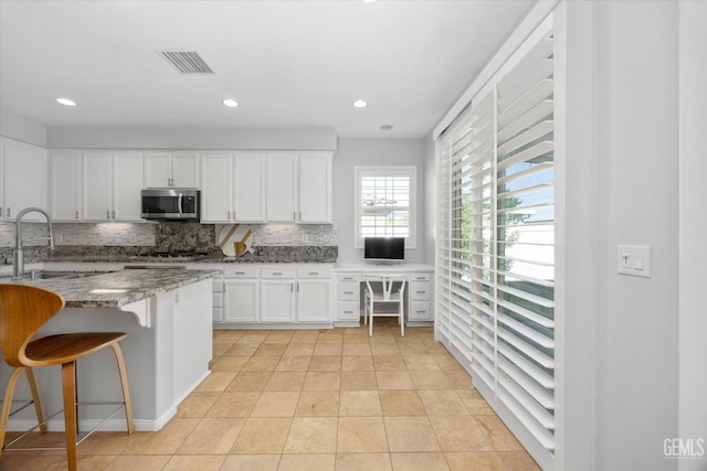 10002 Riata Ln, Bakersfield, CA 93306 - kitchen featuring appliances with stainless steel finishes, a sink, tasteful backsplash, light stone countertops, and white cabinetry