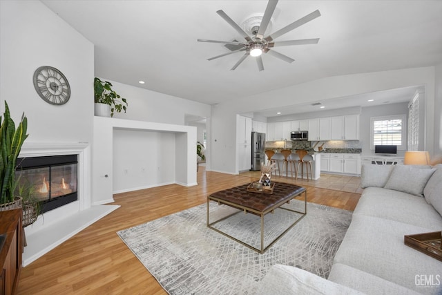 10002 Riata Ln, Bakersfield, CA 93306 - living area with a ceiling fan, light wood-type flooring, a glass covered fireplace, baseboards, and recessed lighting