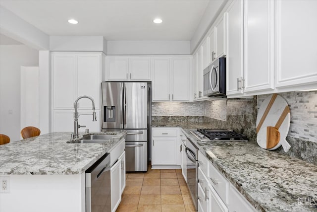 10002 Riata Ln, Bakersfield, CA 93306 - kitchen featuring stainless steel appliances, a sink, white cabinetry, light stone counters, and an island with sink
