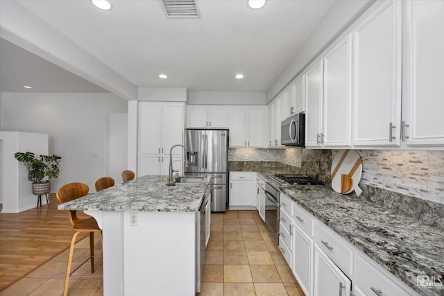10002 Riata Ln, Bakersfield, CA 93306 - kitchen featuring appliances with stainless steel finishes, a sink, a kitchen bar, recessed lighting, and backsplash