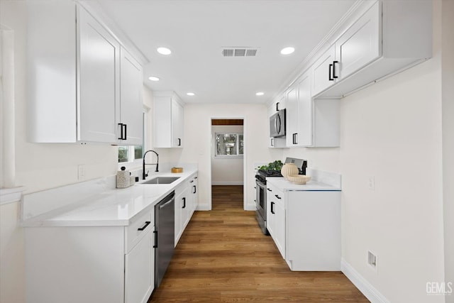 kitchen with white cabinetry, appliances with stainless steel finishes, sink, and hardwood / wood-style flooring