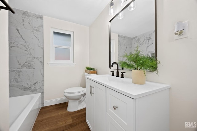 full bathroom featuring vanity, hardwood / wood-style floors, tiled shower / bath, and toilet