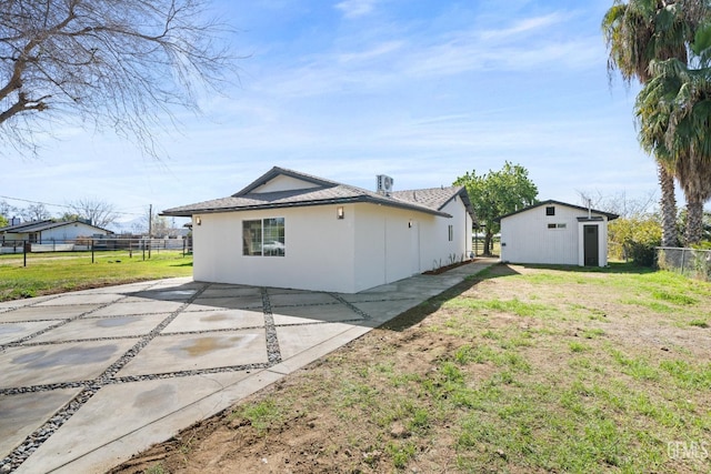 exterior space featuring a patio, an outdoor structure, fence, a yard, and stucco siding