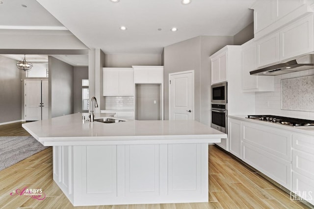 kitchen with appliances with stainless steel finishes, sink, a center island with sink, and white cabinets