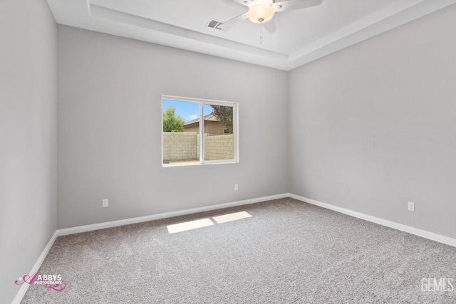 carpeted spare room with ceiling fan and a tray ceiling