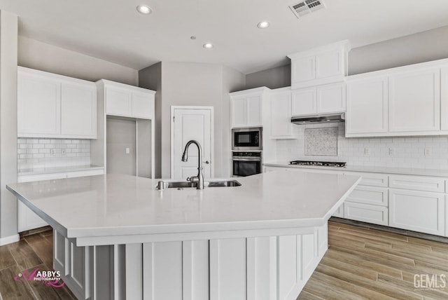 kitchen featuring a large island, sink, built in microwave, and white cabinets