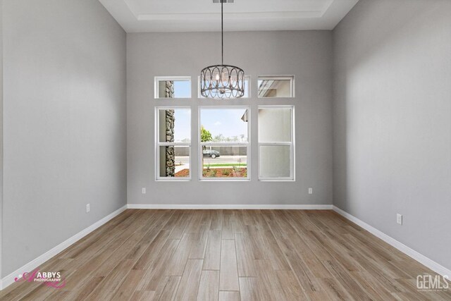 unfurnished room with light hardwood / wood-style floors and a notable chandelier