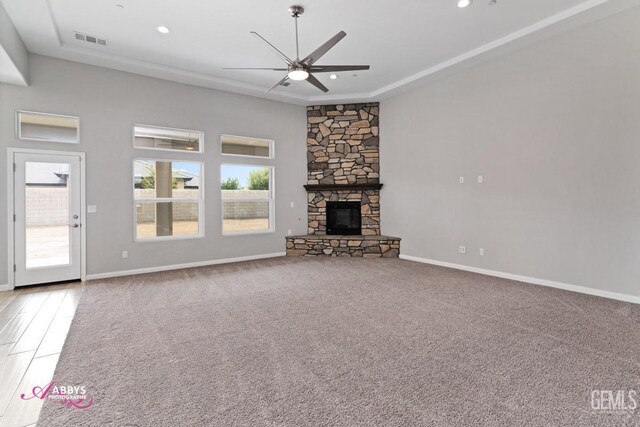 unfurnished living room featuring a stone fireplace, ceiling fan, and carpet flooring