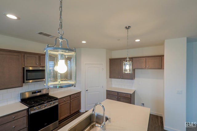 kitchen featuring decorative backsplash, sink, pendant lighting, and appliances with stainless steel finishes