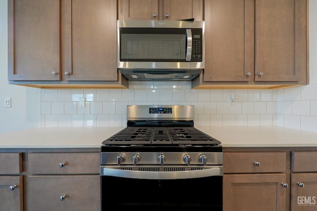 kitchen with light stone countertops, stainless steel appliances, and tasteful backsplash