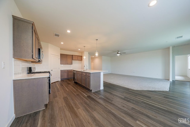 kitchen with pendant lighting, a center island with sink, decorative backsplash, dark hardwood / wood-style flooring, and stainless steel appliances