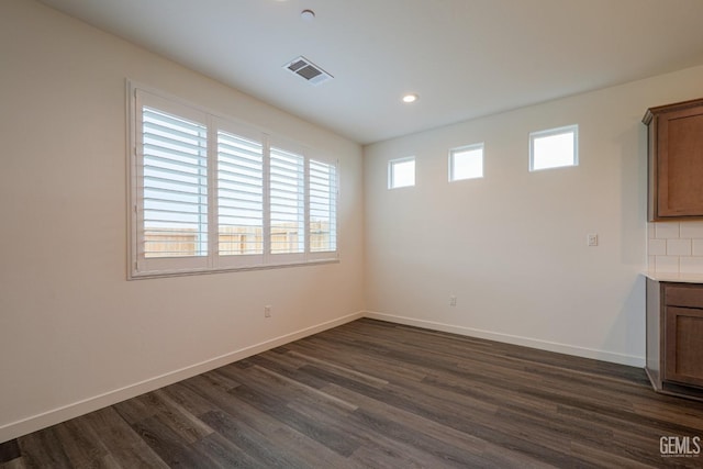 unfurnished room featuring plenty of natural light and dark hardwood / wood-style flooring