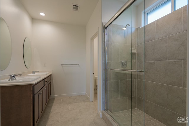 bathroom featuring tile patterned floors, vanity, toilet, and a shower with shower door