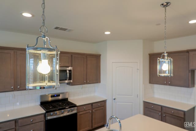 kitchen featuring pendant lighting, sink, backsplash, and appliances with stainless steel finishes