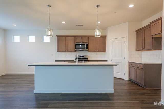 kitchen featuring hanging light fixtures, dark hardwood / wood-style flooring, a kitchen island with sink, and sink