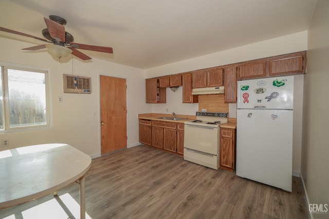 kitchen featuring white appliances, under cabinet range hood, light countertops, and brown cabinetry