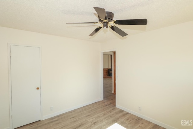 spare room featuring a ceiling fan, light wood-type flooring, a textured ceiling, and baseboards