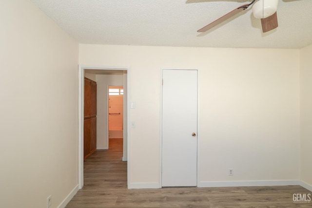 unfurnished bedroom with a ceiling fan, a textured ceiling, baseboards, and wood finished floors