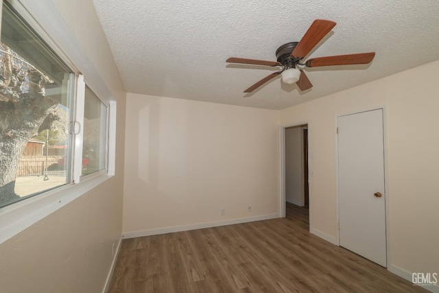 spare room with a textured ceiling, baseboards, and wood finished floors